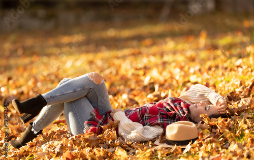 Carefree beautiful brunette lying in the park relaxing during sunny autumn sunset