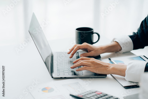 Close-up of business woman's hands Typing on a laptop computer and documents on a desk at the office.