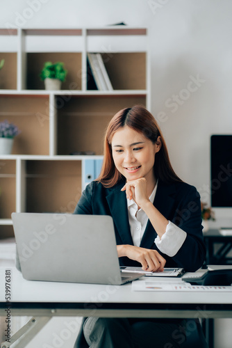 Beautiful Asian businesswoman smiling and working happily on her desk in the office.