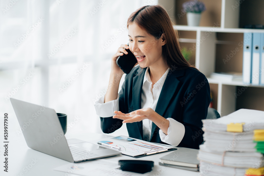 Happy young asian businesswoman sitting on her workplace in the office. Young woman working at laptop in the office Happy young asian businesswoman sitting on her workplace in the office. Young woman working at laptop in the office
