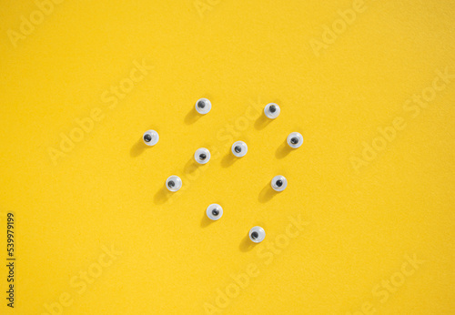 Ten plastic eyes on a yellow background. Idea for Halloween. Holiday postcard. Children's craft. Yellow background. Lots of eyes. Selective focus.