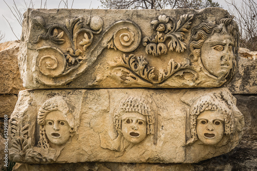 Preserved bas-reliefs with floral ornaments and faces, Demre, Antalya, Turkey. Theater masks. photo