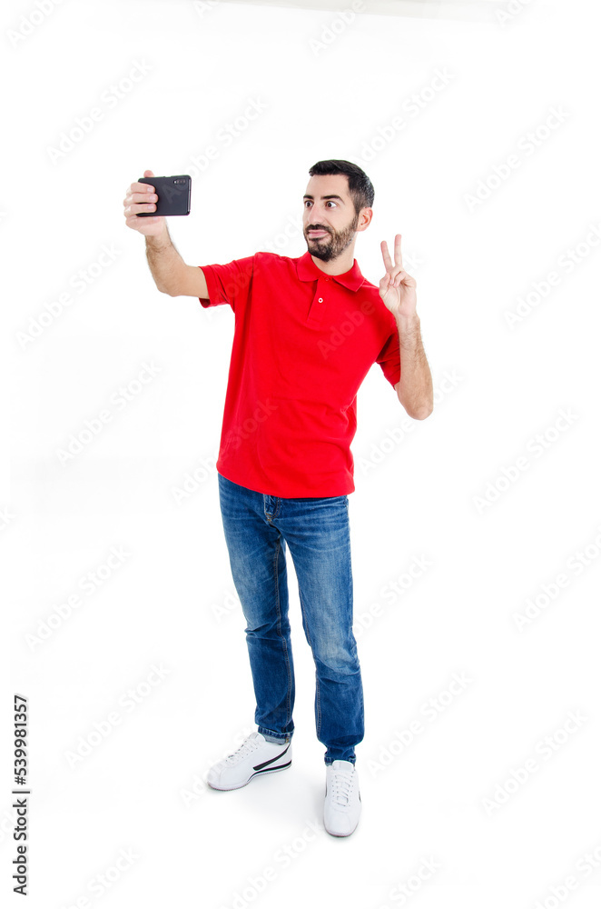Portrait of a smiling attractive man taking a selfie while standing and showing peace gesture isolated over white background. Studio shot