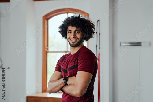 Portrait of happy young middle eastern man with arms crossed at the gym