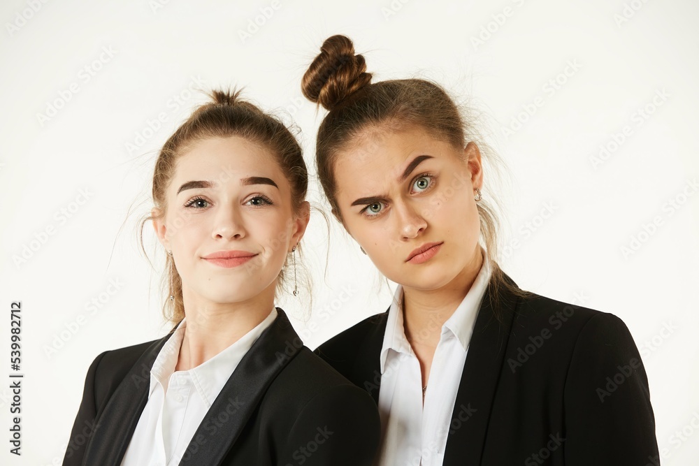 Two girls in office clothes, facial expressions on their faces. Pure white background. The concept of business and corporate relationships in the enterprise. Two girls in office clothes, facial expressions on their faces. Pure white background. The concept of business and corporate relationships in the enterprise.
