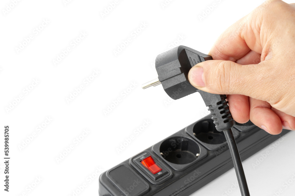 hand connects the plug to the outlet of the surge protector, The concept of starting an electrical device, saving electricity, on isolated white hand connects the plug to the outlet of the surge protector, The concept of starting an electrical device, saving electricity, on isolated white