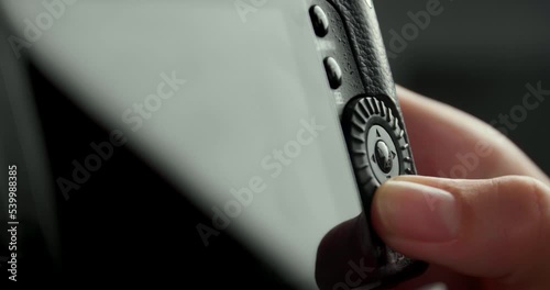 Photographer scrolling button on camera on black background, closeup
