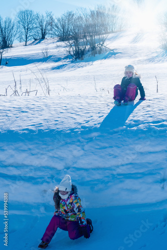 Two best little girlfriends in winter clothes having fun in a snowy mountain.