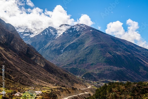 Low-angle of landscape in Chopta valley with yellowing mountains background, and green grass around photo