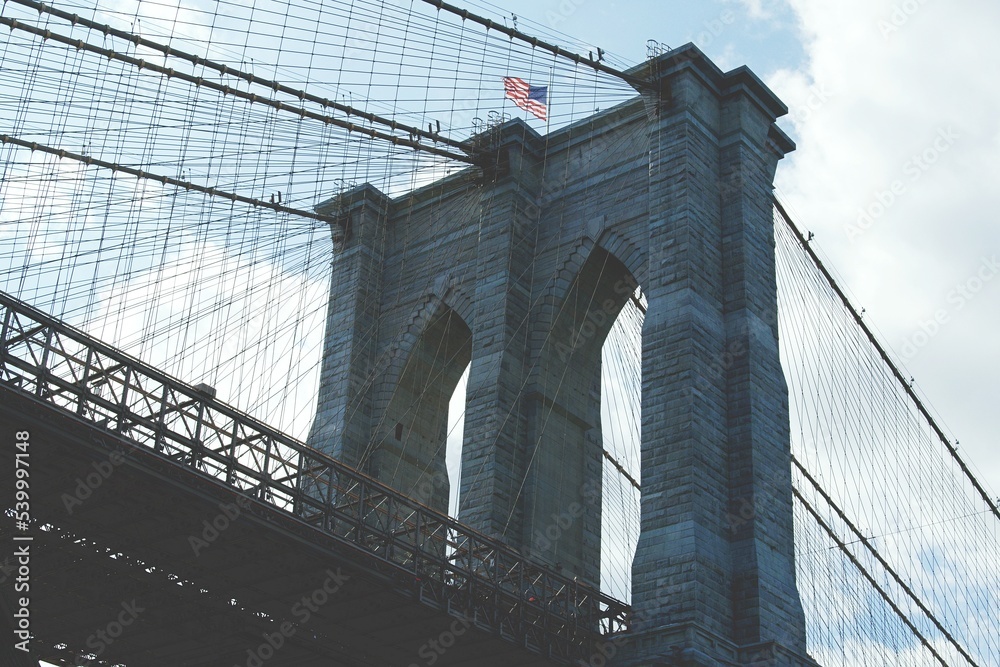 Fototapeta premium Close-up of the Brooklyn Bridge with blue sky and clouds in the background.