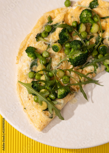 amlet with egg and greens on a white plate on a yellow background photo