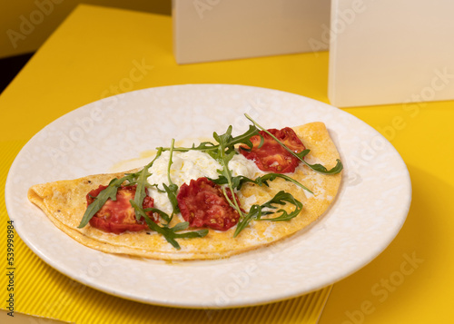 amlet with egg and greens on a white plate on a yellow background photo