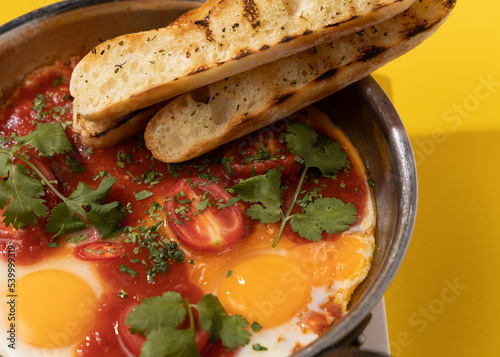 amlet with tomato and toast in a frying pan on a yellow background photo