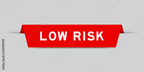 Red color inserted label with word low risk on gray background