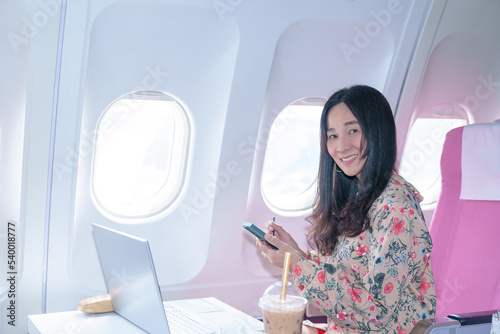  Asian young Businesswoman working using laptop compuer sitting near windows at first class on airplane during flight,Traveling and Business concept photo