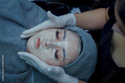 The female dermatologist do face massaged to beautiful girl cosmetology cabinet or beauty clinic. Concept of face cleanser, skin and health care © ND STOCK