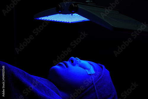 Young woman doing bio light red light therapy on her face Woman blindfolded and irradiated facial skin care  Bio light therapy in beauty clinic   light for facial rejuvenation  Beauty concepts.