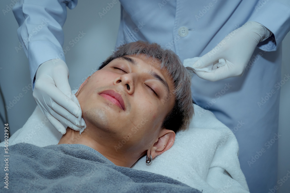 Beautician applying hydro gel mask on the young man face, before laser treatment in beauty salon. Close up side view. , Beauty clinic concepts. Beautician applying hydro gel mask on the young man face, before laser treatment in beauty salon. Close up side view. , Beauty clinic concepts.