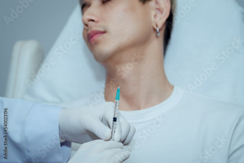 Cosmetologist Doctor makes facial rejuvenation injection procedure for tightening and smoothing wrinkles on face of beautiful young man in beauty skin care salon.   Beauty clinic concepts.
