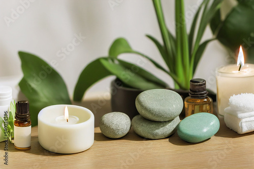 Beauty treatment items for spa procedures on white wooden table with green plant. massage stones  essential oils and sea salt with burning candle. 3d illustration