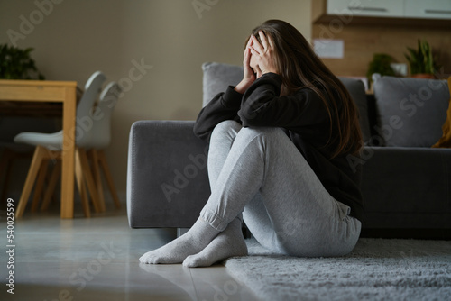 Caucasian broken woman sitting at the floor in living room photo
