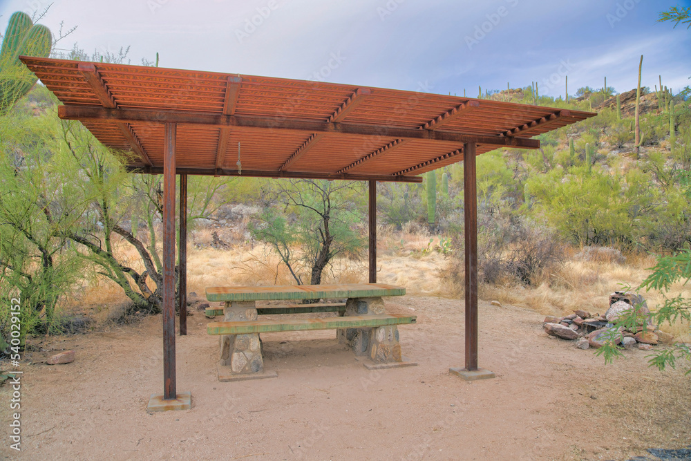 Concrete dining table with seats under the rusty metal pergola roof at Tucson, Arizona