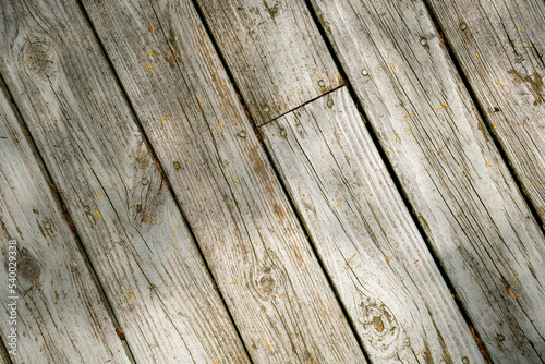 Dilapidated wooden deck flooring win dappled shadows.