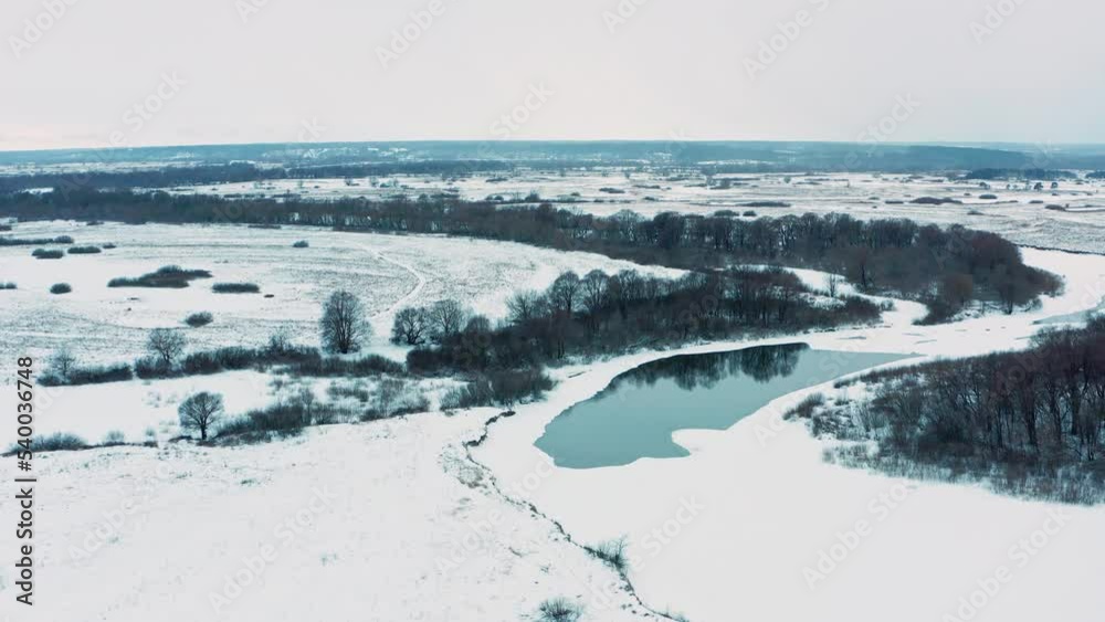Drone is flying over a frozen river with thawed areas. Drone flies over snowy flat landscape. Aerial view of the snowy valley in the winter. Beautiful white landscape in the winter, in Europe. Drone is flying over a frozen river with thawed areas. Drone flies over snowy flat landscape. Aerial view of the snowy valley in the winter. Beautiful white landscape in the winter, in Europe.