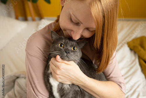Smiling woman embracing fluffy cat in bedroom
