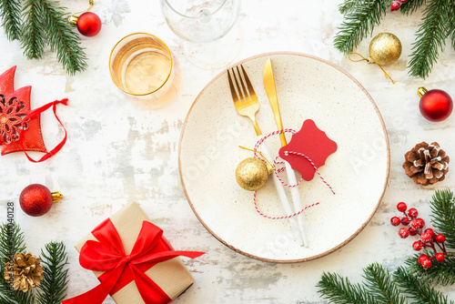 Christmas table setting with plate, cutlery and christmas decorations on white background.