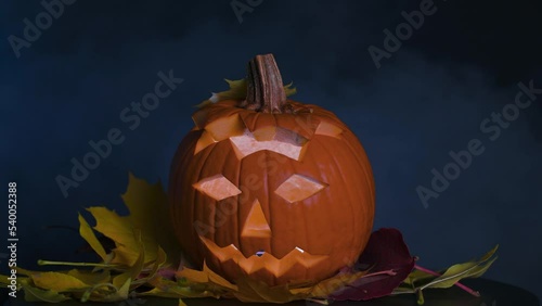 Festive pumpkin for Halloween in the form of a jack-o'-lantern, in autumn leaves