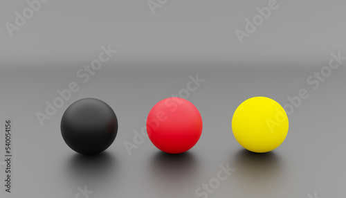 3d-rendering of three balls with the colours black, red and yellow as a symbol for the colours of the german national flag in front of a black background