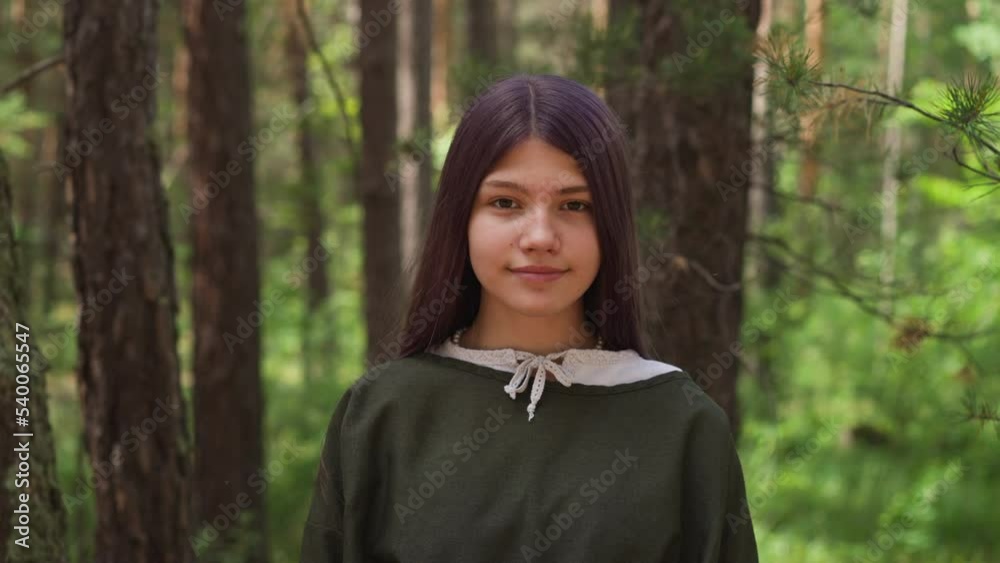 Dark-haired girl in medieval dress smiles in woods, close-up Dark-haired girl in medieval dress smiles in woods, close-up