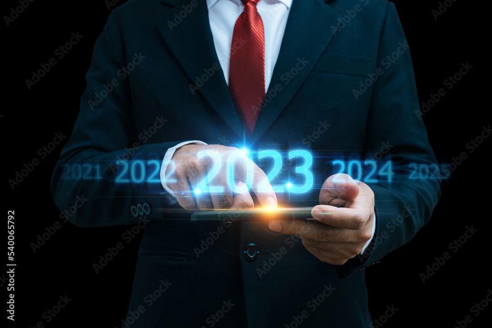 Obraz premium 2023. smart businessman investor using mobile phone with virtual screen on dark background, business trend, change from 2022 to 2023, strategy, investment, business planning and happy new year concept