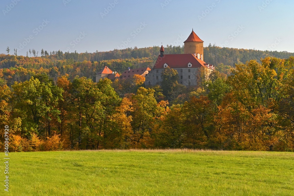 Beautiful autumn landscape with old castle Veveri at sunset and beautiful blue sky with clouds. Colorful nature background on autumn season. Brno - Czech Republic.