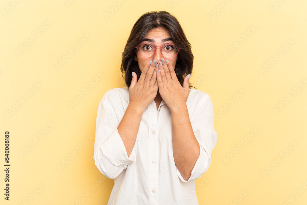Young Indian woman isolated on yellow background shocked, covering mouth with hands, anxious to discover something new. Young Indian woman isolated on yellow background shocked, covering mouth with hands, anxious to discover something new.