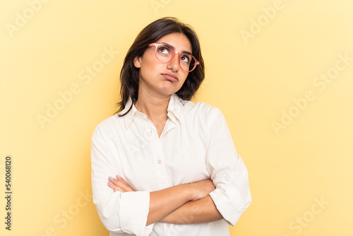 Young Indian woman isolated on yellow background tired of a repetitive task.