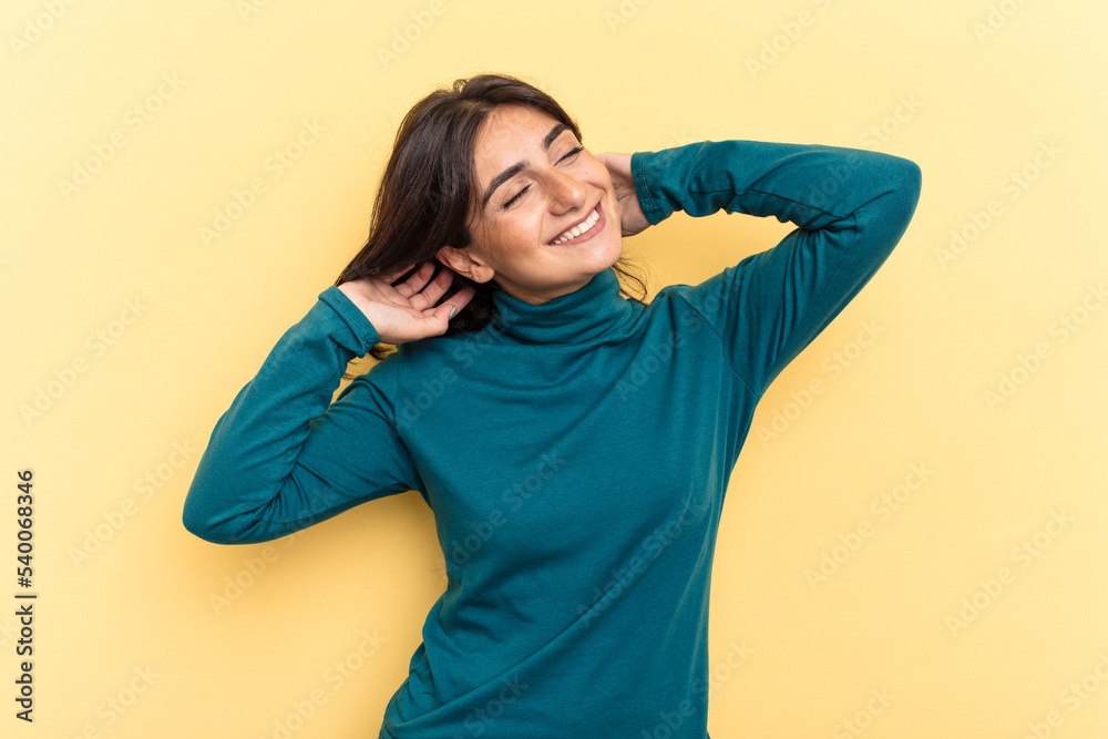 Young Indian woman isolated on yellow background feeling confident, with hands behind the head. Young Indian woman isolated on yellow background feeling confident, with hands behind the head.