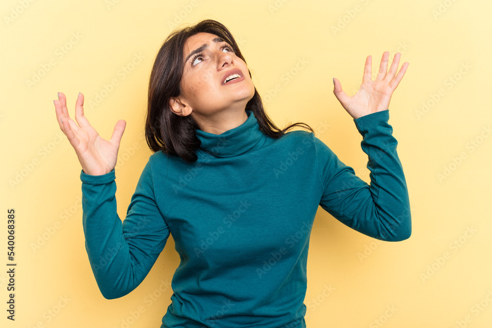 Young Indian woman isolated on yellow background screaming to the sky, looking up, frustrated. Young Indian woman isolated on yellow background screaming to the sky, looking up, frustrated.
