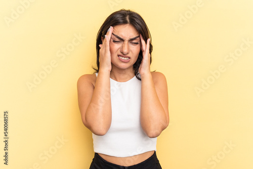 Young Indian woman isolated on yellow background touching temples and having headache.