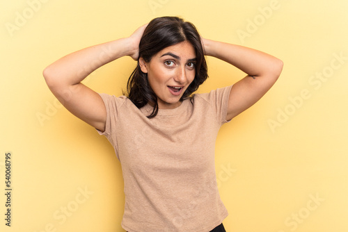 Young Indian woman isolated on yellow background screaming, very excited, passionate, satisfied with something.