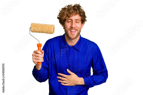 Young painter man holding a roll isolated on white background laughing and having fun.