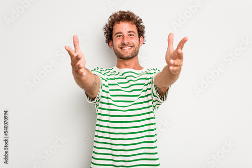 Young caucasian curly hair man isolated on white background feels confident giving a hug to the camera.