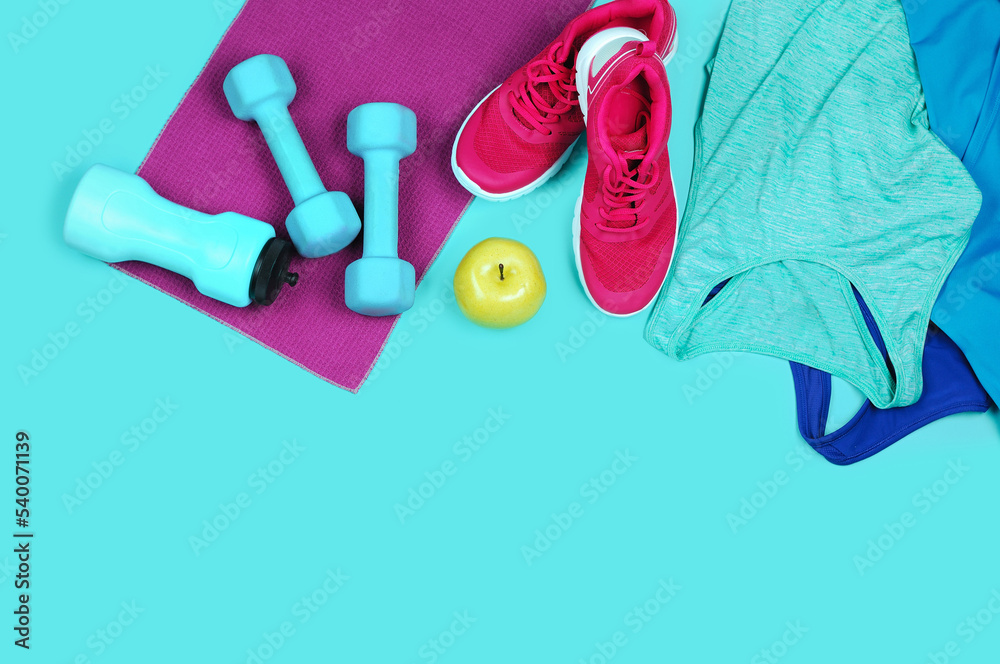 dumbbells, water flask, towel, jogging tops and sneakers, green apple on teal background dumbbells, water flask, towel, jogging tops and sneakers, green apple on teal background