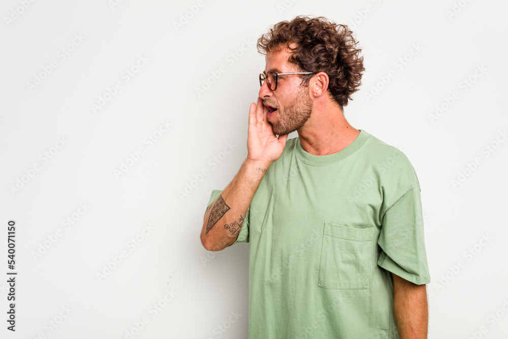 Young caucasian curly hair man isolated on white background is saying a secret hot braking news and looking aside Young caucasian curly hair man isolated on white background is saying a secret hot braking news and looking aside