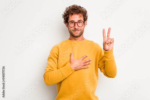 Photos Young caucasian curly hair man isolated on white background taking an oath, putting hand on chest