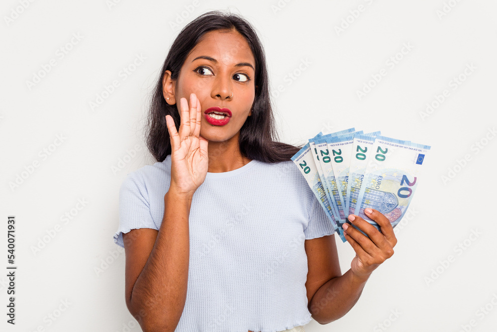 Young indian woman holding a banknotes isolated on white background is saying a secret hot braking news and looking aside Young indian woman holding a banknotes isolated on white background is saying a secret hot braking news and looking aside