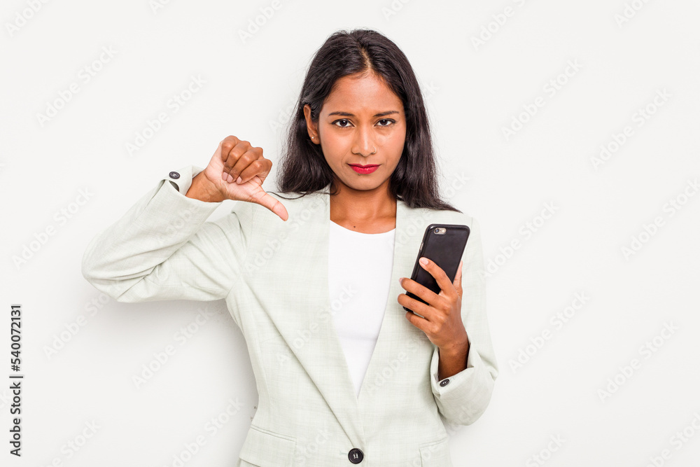 Young business Indian woman holding a mobile phone isolated on white background showing a dislike gesture, thumbs down. Disagreement concept. Young business Indian woman holding a mobile phone isolated on white background showing a dislike gesture, thumbs down. Disagreement concept.