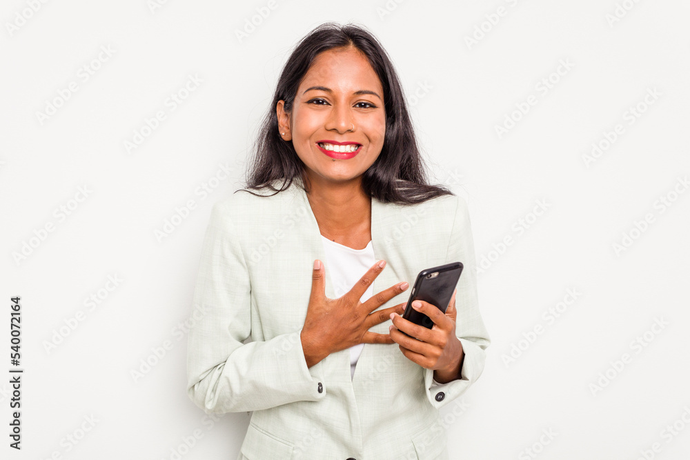 Young business Indian woman holding a mobile phone isolated on white background laughs out loudly keeping hand on chest. Young business Indian woman holding a mobile phone isolated on white background laughs out loudly keeping hand on chest.