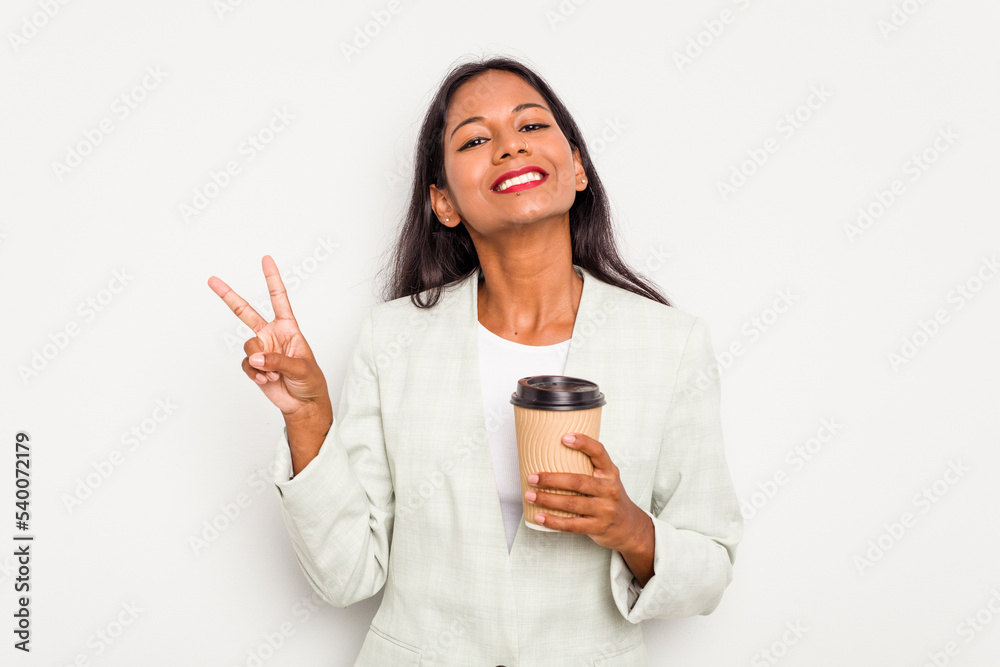 Young business Indian woman holding takeaway coffee isolated on white background joyful and carefree showing a peace symbol with fingers. Young business Indian woman holding takeaway coffee isolated on white background joyful and carefree showing a peace symbol with fingers.